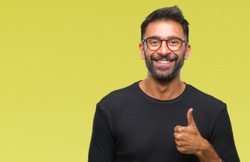 Adult hispanic man wearing glasses over isolated background doing happy thumbs up gesture with hand. Approving expression looking at the camera with showing success.
