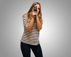 Young Woman Looking Through A Camera against a grey background