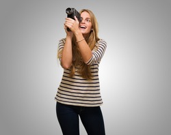 Woman Looking Through A Camera against a grey background
