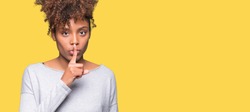 Beautiful young african american woman over isolated background asking to be quiet with finger on lips. Silence and secret concept.