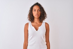 Young brazilian woman wearing casual t-shirt standing over isolated white background with serious expression on face. Simple and natural looking at the camera.