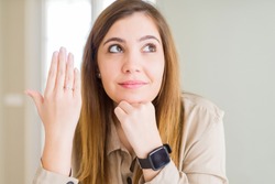 Beautiful young woman showing engagement ring on hand serious face thinking about question, very confused idea