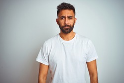 Young indian man wearing t-shirt standing over isolated white background depressed and worry for distress, crying angry and afraid. Sad expression.