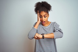 African american woman wearing navy striped t-shirt standing over isolated white background Looking at the watch time worried, afraid of getting late