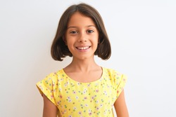 Young beautiful child girl wearing yellow floral dress standing over isolated white background with a happy face standing and smiling with a confident smile showing teeth
