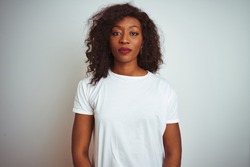 Young african american woman wearing t-shirt standing over isolated white background Relaxed with serious expression on face. Simple and natural looking at the camera.