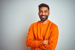 Young indian man wearing orange sweater over isolated white background happy face smiling with crossed arms looking at the camera. Positive person.