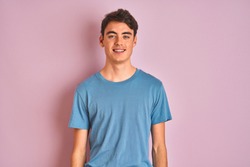 Teenager boy wearing casual t-shirt standing over blue isolated background with a happy and cool smile on face. Lucky person.