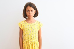 Young beautiful child girl wearing yellow floral dress standing over isolated white background skeptic and nervous, frowning upset because of problem. Negative person.