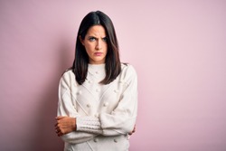 Young brunette woman with blue eyes wearing casual sweater over isolated pink background skeptic and nervous, disapproving expression on face with crossed arms. Negative person.