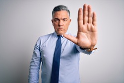 Middle age handsome grey-haired business man wearing elegant shirt and tie doing stop sing with palm of the hand. Warning expression with negative and serious gesture on the face.