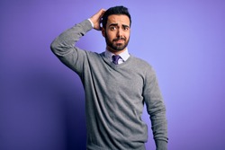 Handsome businessman with beard wearing casual tie standing over purple background confuse and wonder about question. Uncertain with doubt, thinking with hand on head. Pensive concept.