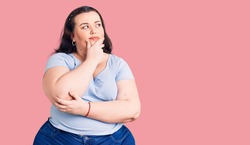 Young plus size woman wearing casual clothes with hand on chin thinking about question, pensive expression. smiling with thoughtful face. doubt concept. 
