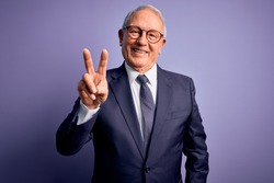 Grey haired senior business man wearing glasses and elegant suit and tie over purple background smiling looking to the camera showing fingers doing victory sign. Number two.