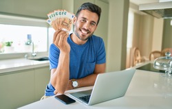 Young handsome man smiling happy holding euro banknotes at home