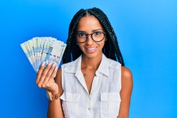 Beautiful hispanic woman holding south african 100 rand banknotes looking positive and happy standing and smiling with a confident smile showing teeth 
