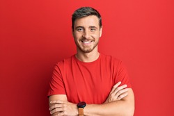Handsome caucasian man wearing casual red tshirt happy face smiling with crossed arms looking at the camera. positive person. 