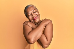 Senior african american woman wearing casual style with sleeveless shirt hugging oneself happy and positive, smiling confident. self love and self care 