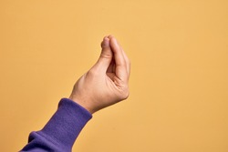 Hand of caucasian young man showing fingers over isolated yellow background doing Italian gesture with fingers together, communication gesture movement