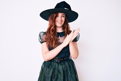 Young beautiful woman wearing witch halloween costume clapping and applauding happy and joyful, smiling proud hands together 