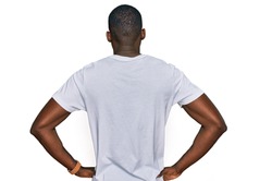 Young african american man wearing casual white t shirt standing backwards looking away with arms on body 