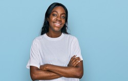 Young african american woman wearing casual white t shirt happy face smiling with crossed arms looking at the camera. positive person. 