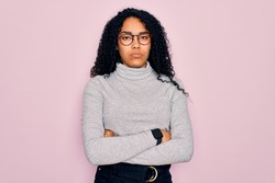 Young african american woman wearing turtleneck sweater and glasses over pink background skeptic and nervous, disapproving expression on face with crossed arms. Negative person.