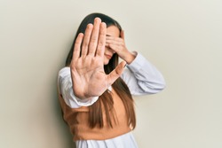 Beautiful brunette young woman wearing casual clothes covering eyes with hands and doing stop gesture with sad and fear expression. embarrassed and negative concept. 
