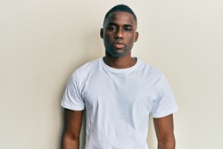 Young african american man wearing casual white t shirt with serious expression on face. simple and natural looking at the camera. 