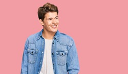 Handsome caucasian man wearing casual denim jacket looking away to side with smile on face, natural expression. laughing confident. 