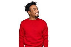 Young african american man with beard wearing casual winter sweater looking away to side with smile on face, natural expression. laughing confident. 