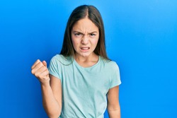 Beautiful brunette little girl wearing casual white t shirt angry and mad raising fist frustrated and furious while shouting with anger. rage and aggressive concept. 