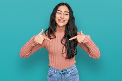 Hispanic teenager girl with dental braces wearing casual clothes looking confident with smile on face, pointing oneself with fingers proud and happy. 