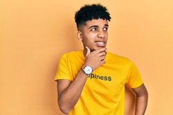Young african american man wearing t shirt with happiness word message thinking worried about a question, concerned and nervous with hand on chin 