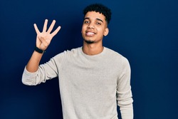 Young african american man wearing casual clothes showing and pointing up with fingers number four while smiling confident and happy. 
