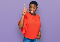 Young african american woman wearing casual clothes pointing finger up with successful idea. exited and happy. number one. 