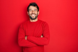 Handsome man with beard wearing casual red sweater happy face smiling with crossed arms looking at the camera. positive person. 
