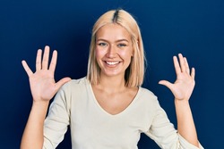 Beautiful blonde woman wearing casual sweater showing and pointing up with fingers number ten while smiling confident and happy. 