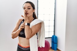 Young brunette woman wearing sportswear and towel at the gym hand on mouth telling secret rumor, whispering malicious talk conversation 
