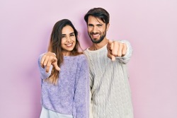 Young hispanic couple wearing casual clothes pointing to you and the camera with fingers, smiling positive and cheerful 