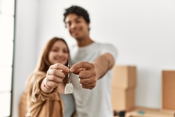 Young couple smiling happy holding key of new home.