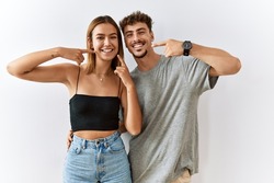 Young beautiful couple standing together over isolated background smiling cheerful showing and pointing with fingers teeth and mouth. dental health concept. 