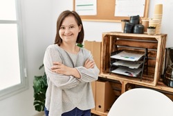 Brunette woman with down syndrome working standing with crossed arms at business office