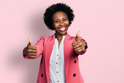 African american woman with afro hair wearing business jacket approving doing positive gesture with hand, thumbs up smiling and happy for success. winner gesture. 