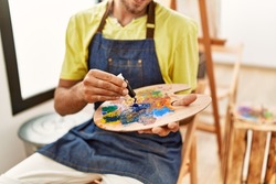 Artist man mixing colors on palette at art studio.