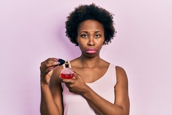 Young african american woman holding perfume depressed and worry for distress, crying angry and afraid. sad expression. 