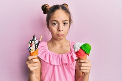 Beautiful brunette little girl eating ice cream cones depressed and worry for distress, crying angry and afraid. sad expression. 