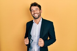 Handsome man with beard wearing business suit holding jacket smiling with a happy and cool smile on face. showing teeth. 