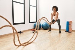 Young african american woman smiling confident training with battle rope at sport center