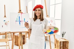Young artist woman painting on a canvas at art studio with a happy and cool smile on face. lucky person. 